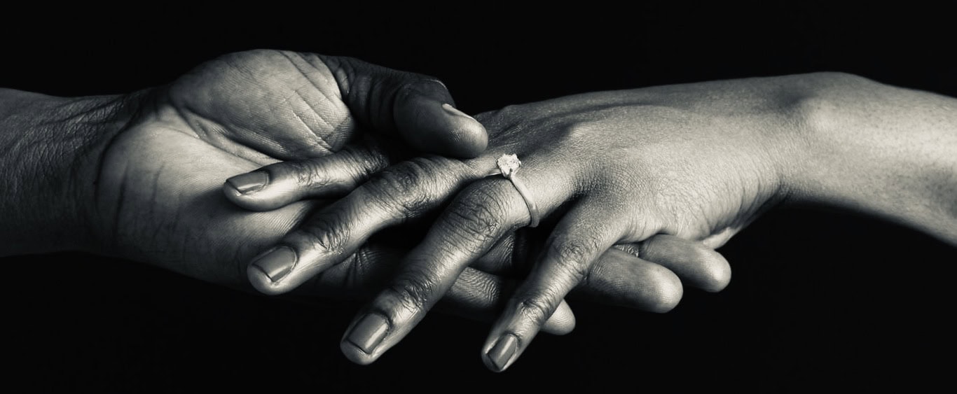 Close-up of two hands, one dark-skinned and one light-skinned, holding each other.
