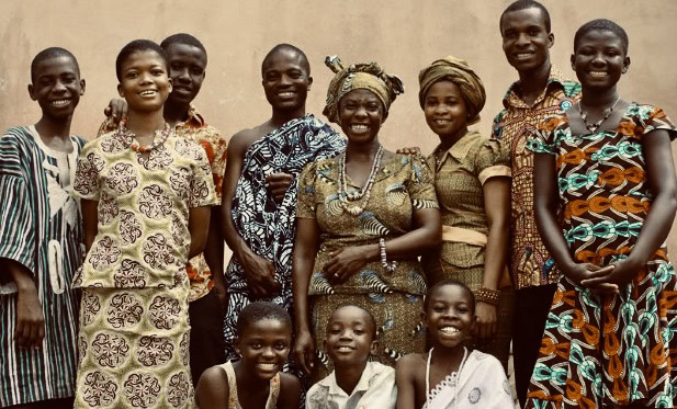 Group of smiling Black South African women and children in traditional attire.