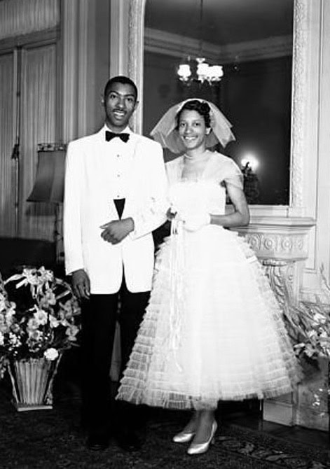 Elegant couple in wedding attire at a formal indoor event.