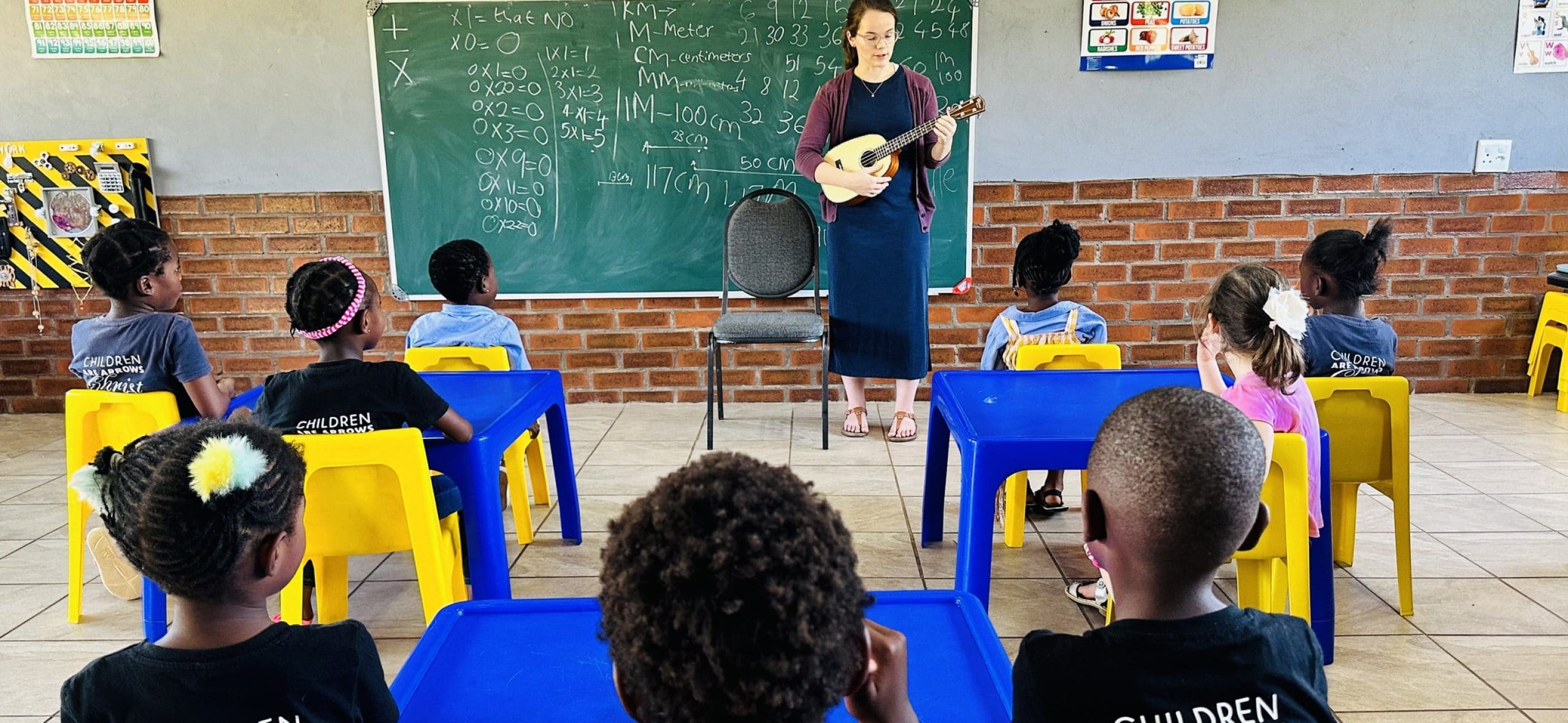 Teacher playing guitar in classroom with students.