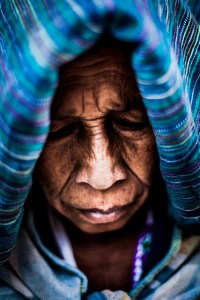 Close-up of elderly woman with traditional head covering and deep facial lines.