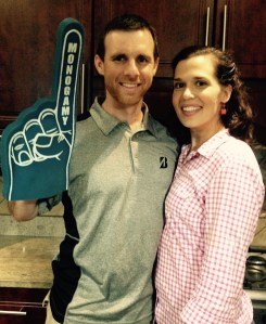 Smiling couple holding a foam finger at a gathering.