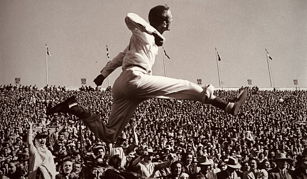 A man leaps over a crowd during a cultural festival in black and white.