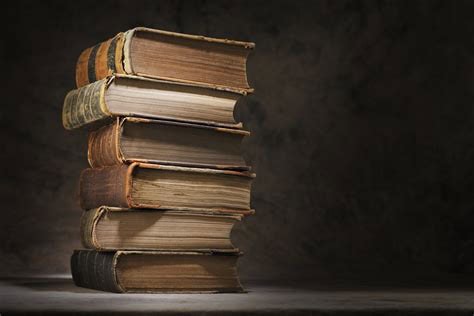 Stack of old, worn books on a dark background for book selection tips.