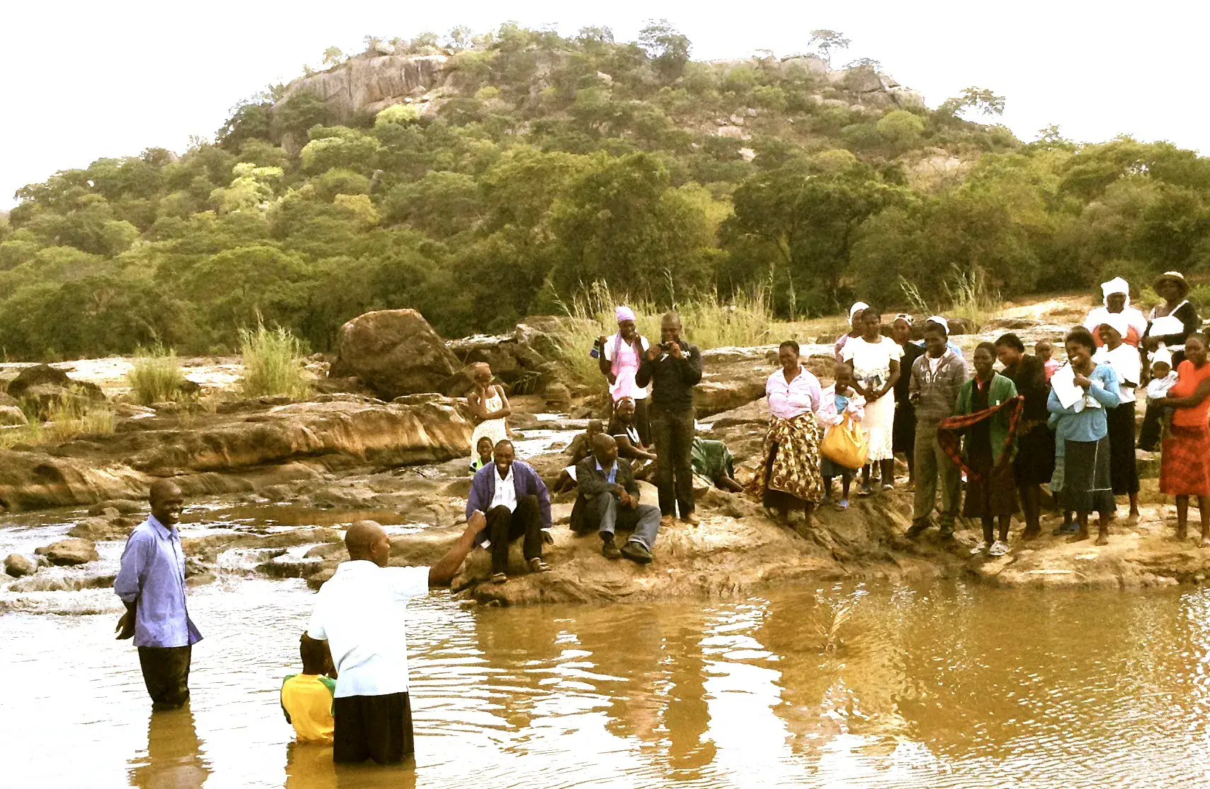 Group of people gathered by Limpopo River for community event.