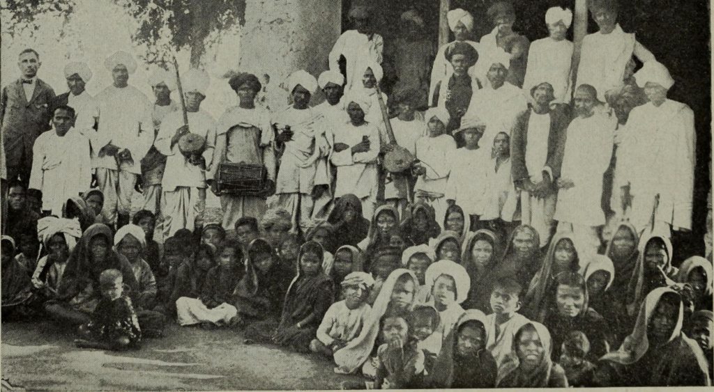 Group of missionaries and local community members in a historical setting.