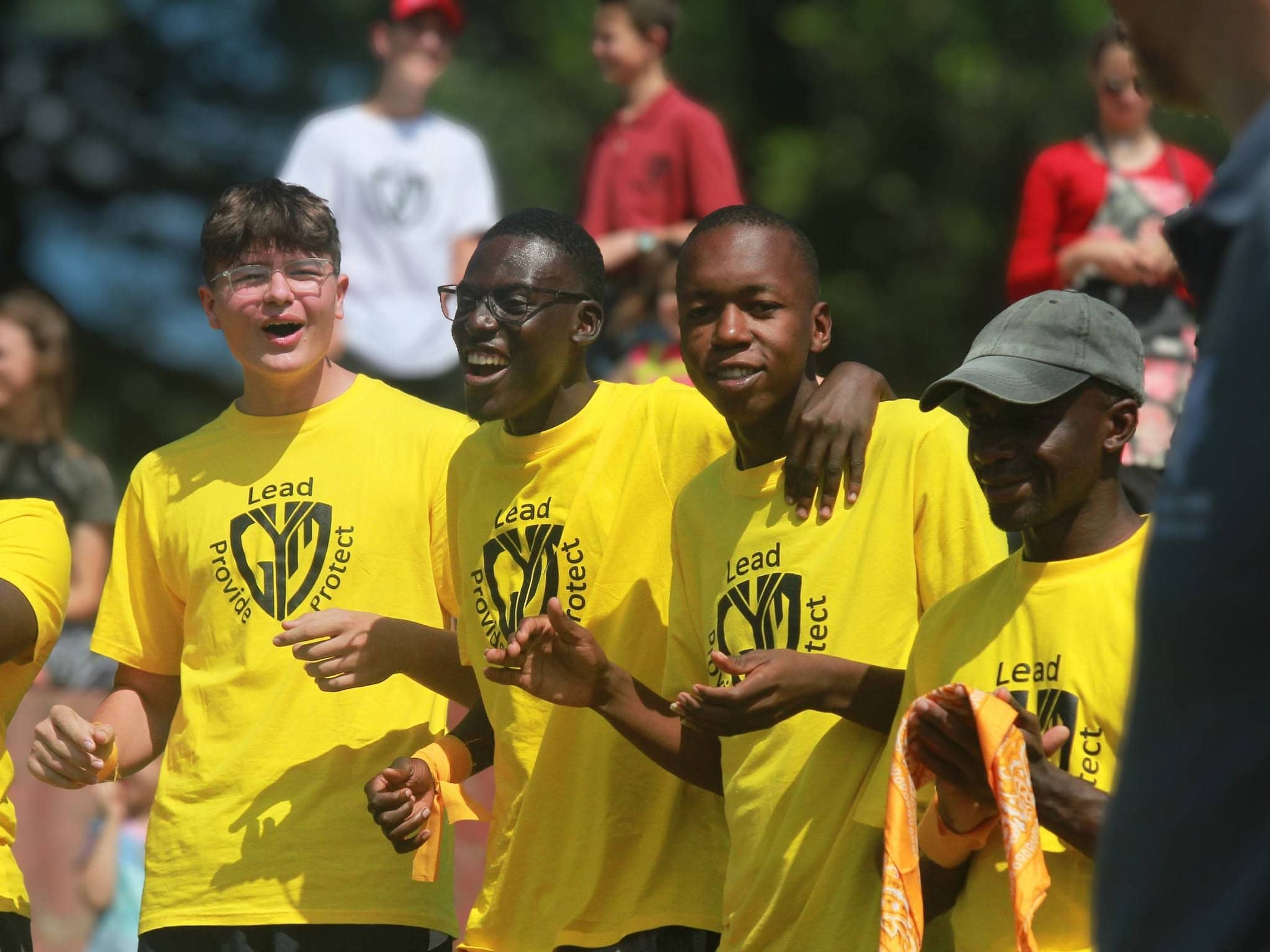 Group of young men wearing yellow Lead Project shirts during an outdoor Christian youth camp.