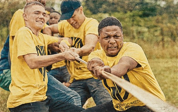 Young men in yellow GYM Camp shirts pulling a rope in a tug of war